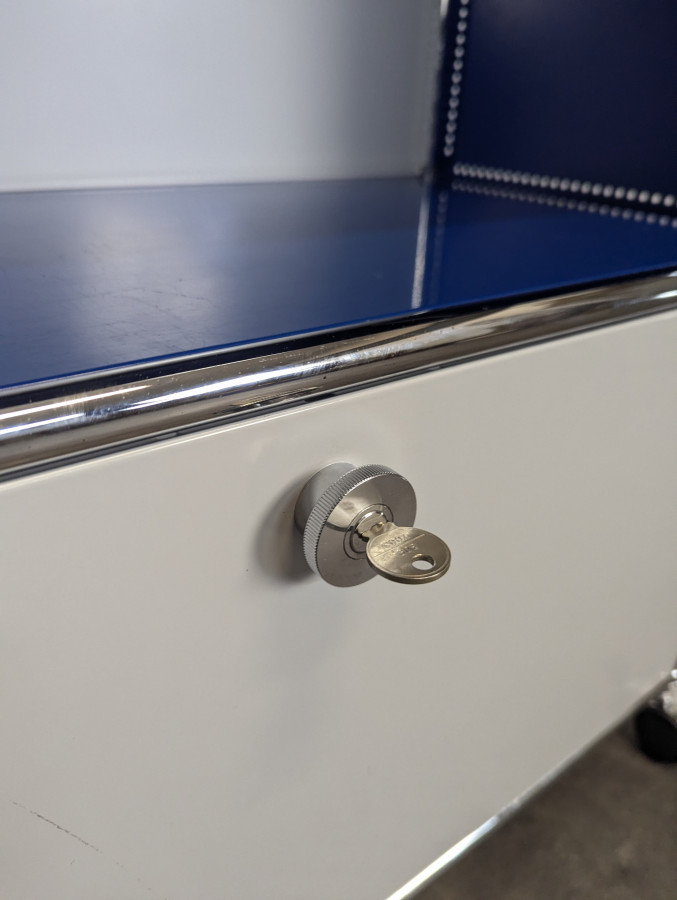 Meuble USM Haller bleu gentiane et blanc à porte abattante sur roulettes