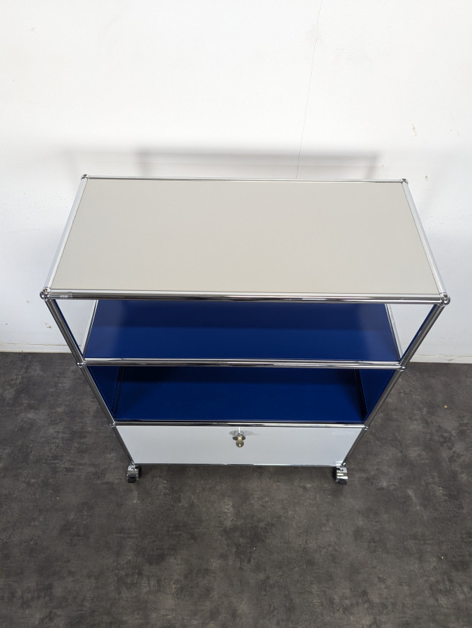 Meuble USM Haller bleu gentiane et blanc à porte abattante sur roulettes
