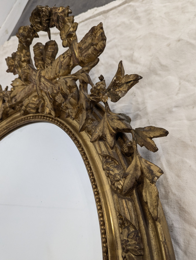 Miroir ovale de style Louis XVI fin XIXe en bois et stuc doré