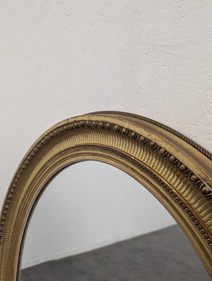 Miroir ovale en bois et stuc doré à motif de raies de coeur