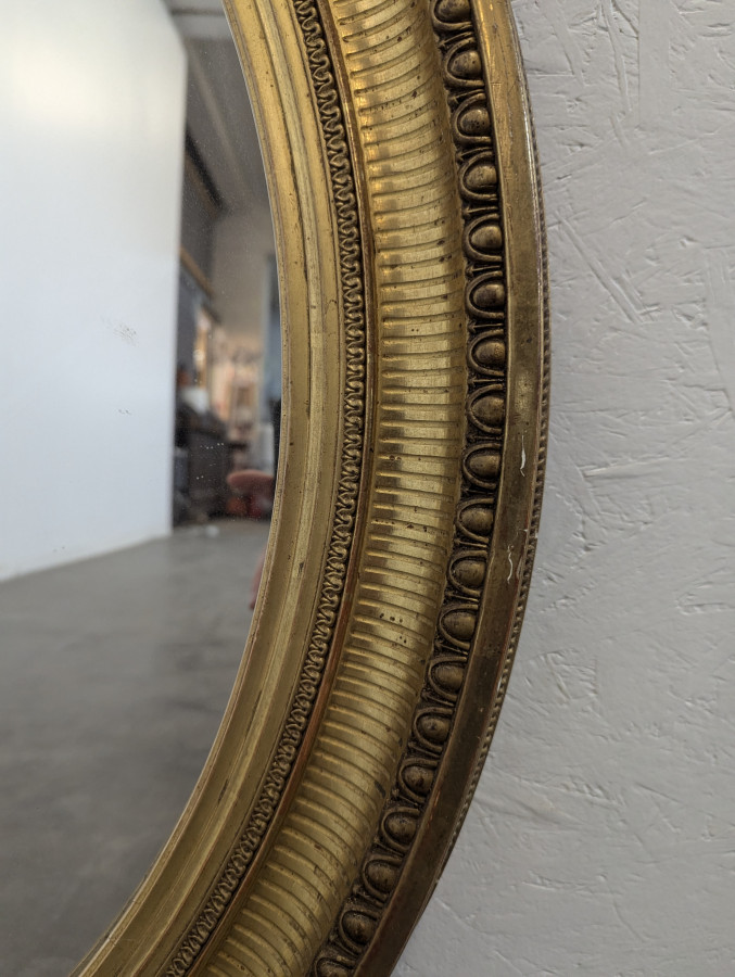 Miroir ovale en bois et stuc doré à motif de raies de coeur