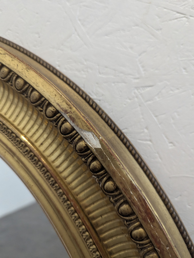 Miroir ovale en bois et stuc doré à motif de raies de coeur