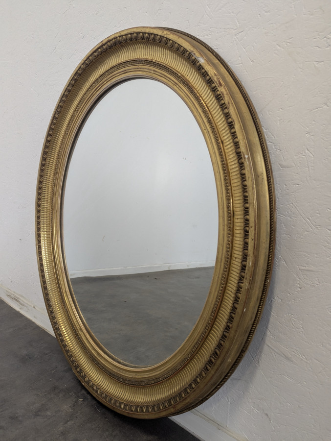 Miroir ovale en bois et stuc doré à motif de raies de coeur
