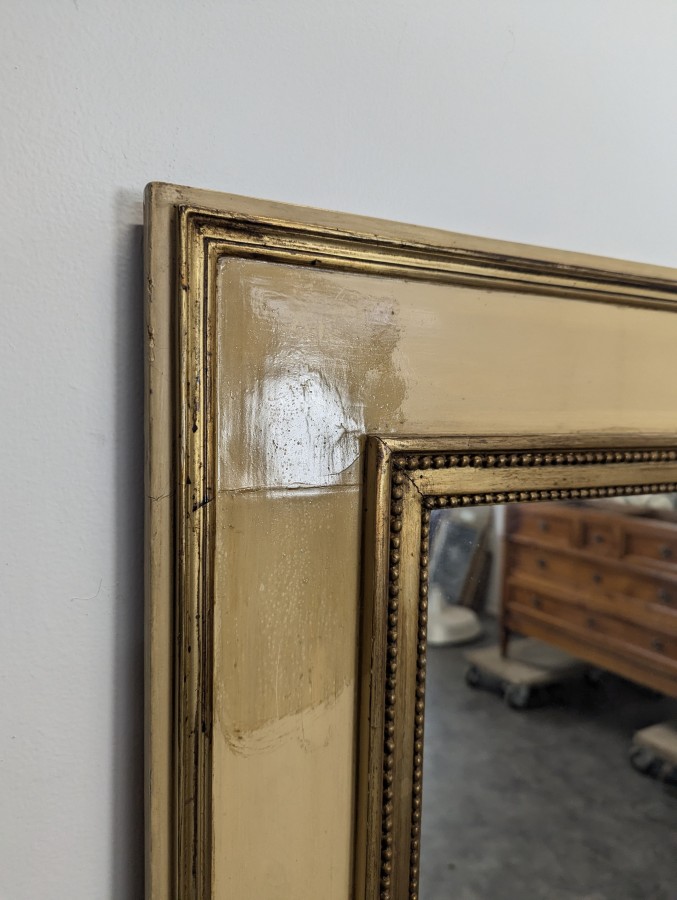 Miroir de style Louis XVI en bois laqué crème et doré à rang de perles