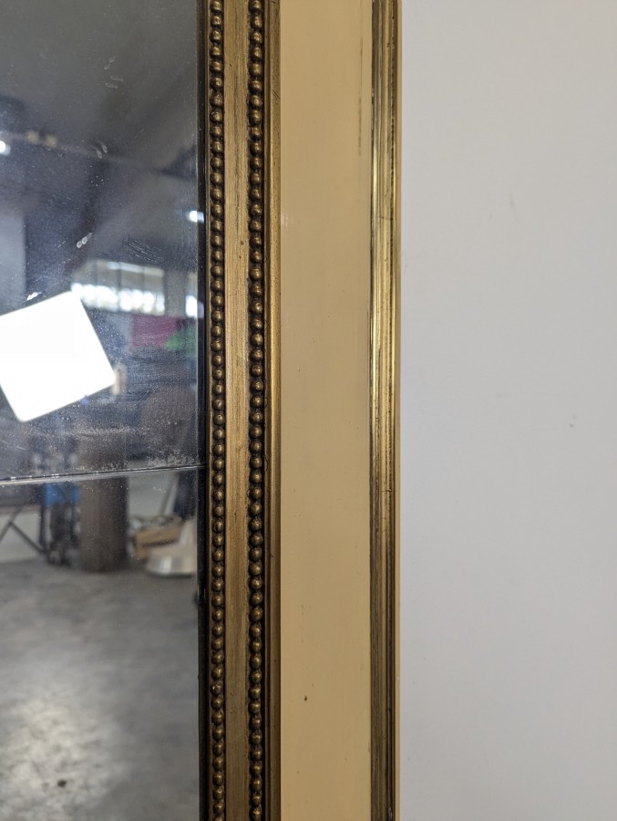 Miroir de style Louis XVI en bois laqué crème et doré à rang de perles